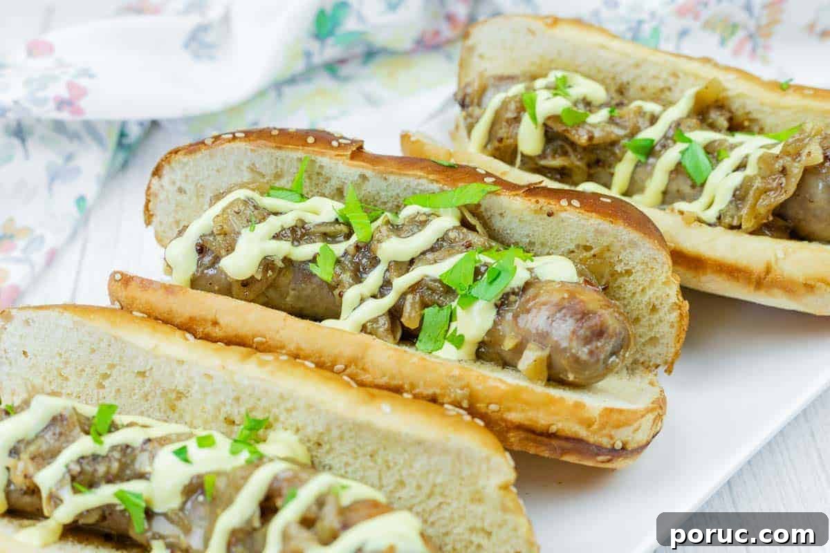 25 Comfort-Food Recipes That Satisfy Every Craving 11 Three Beer Braised Brats in toasted buns topped with sautéed onions, chopped parsley, and a drizzle of yellow sauce, served on a white plate.