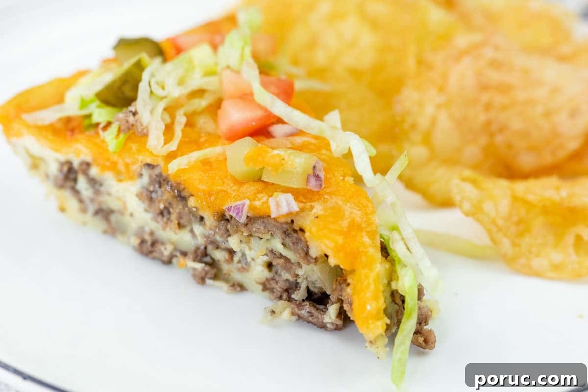 25 Comfort-Food Recipes That Satisfy Every Craving 13 A slice of cheeseburger pie topped with shredded lettuce, diced tomato, onions, and pickles, served with potato chips on a white plate.