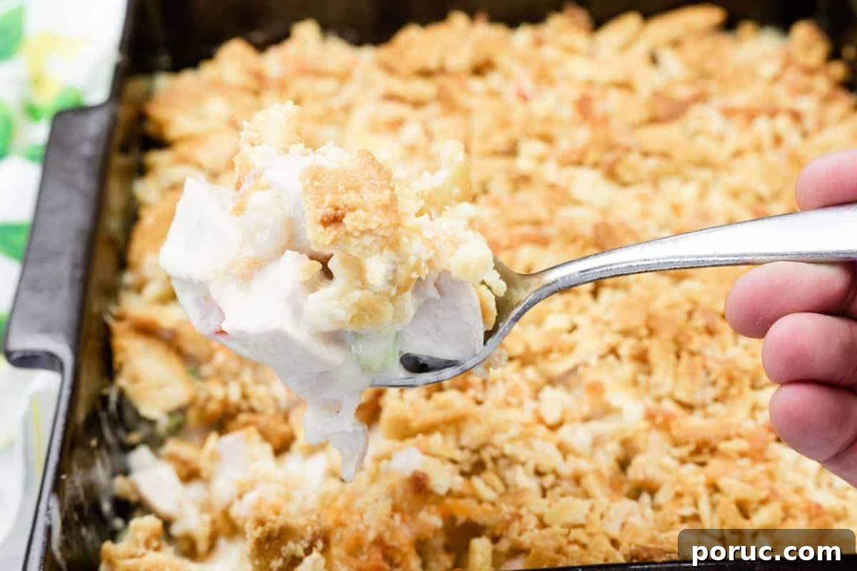 25 Comfort-Food Recipes That Satisfy Every Craving 3 A hand holds a spoonful of Ritz Cracker Chicken Casserole with Cheese, with the casserole dish in the background.