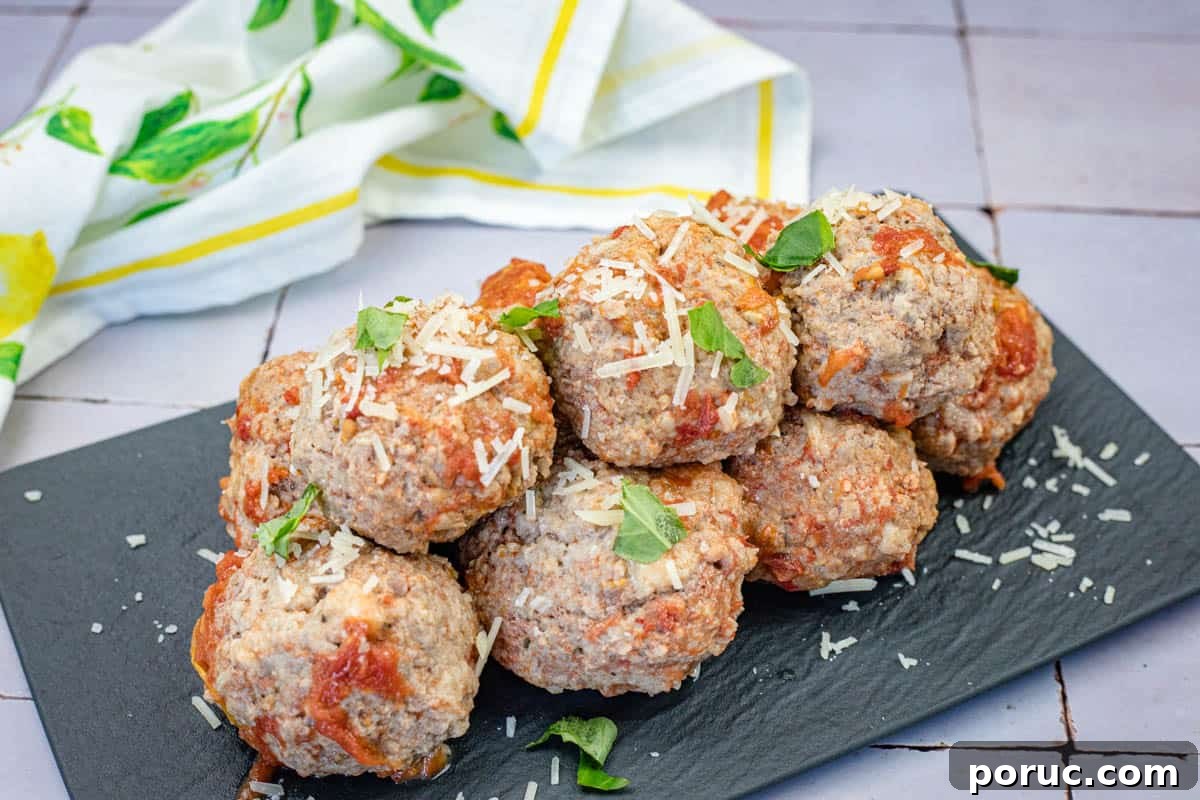 25 Comfort-Food Recipes That Satisfy Every Craving 26 A stack of giant meatballs garnished with grated cheese and fresh herbs served on a black rectangular slate plate.