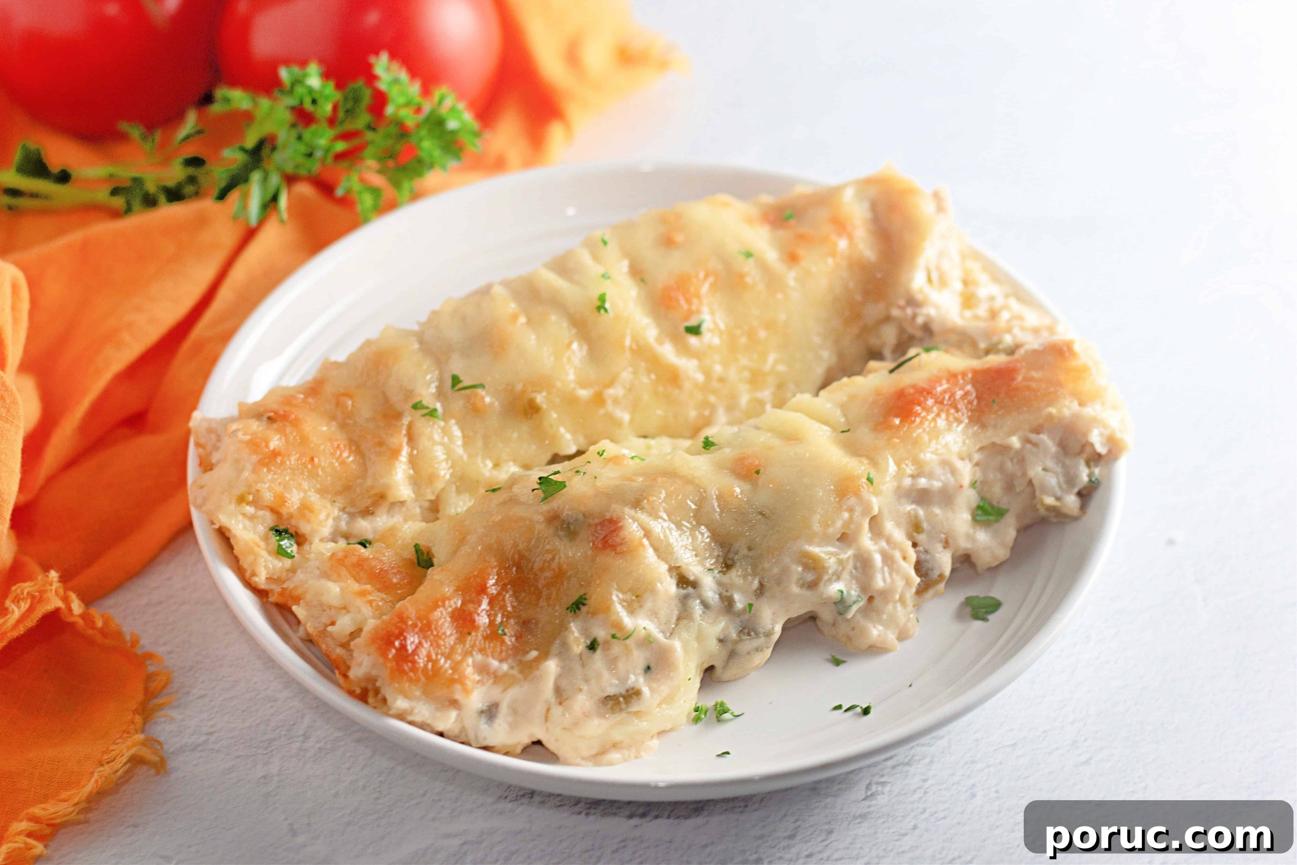 25 Comfort-Food Recipes That Satisfy Every Craving 5 Two White Chicken Enchiladas filled with creamy sauce and topped with melted cheese, served on a white plate with a garnish of chopped parsley.
