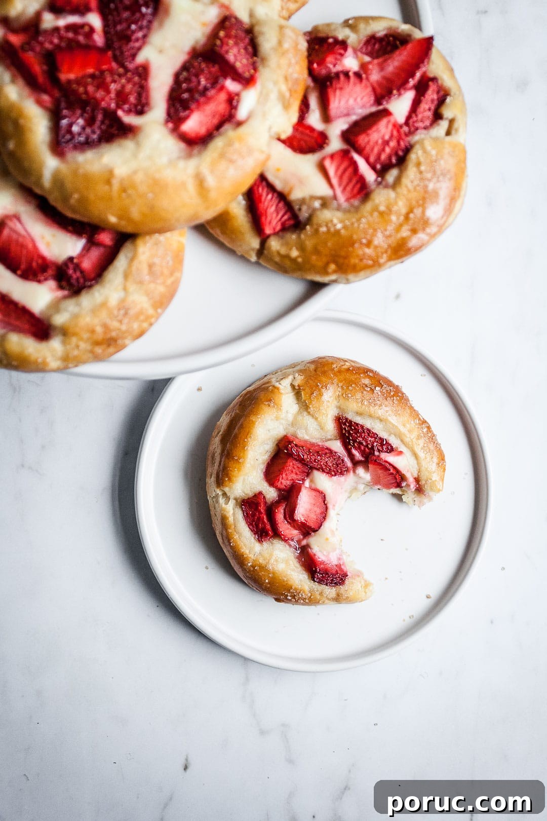 Strawberry Cream Cheese Brioche with Orange Blossom Water 11 Brioche pastry on a white plate and marble background with more pastries piled on a plate nearby