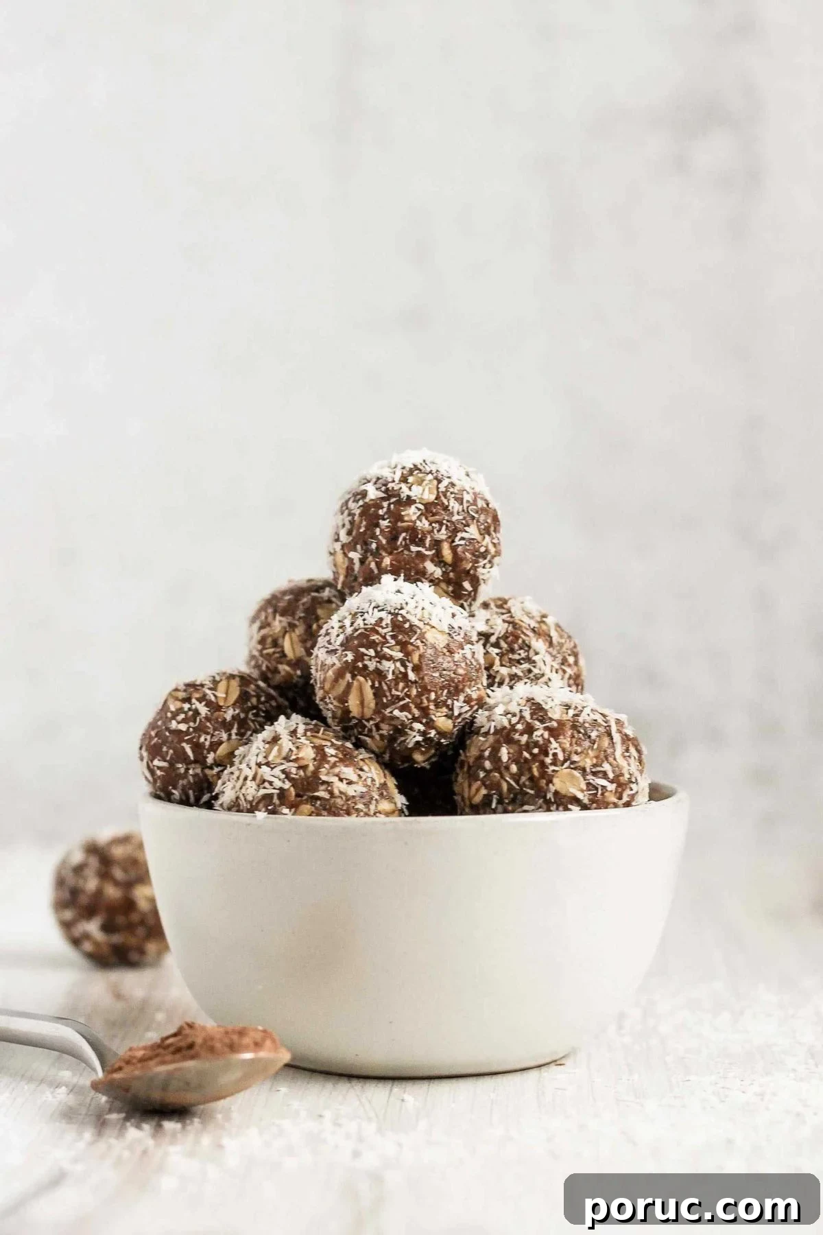 Chocolate Coconut Peanut Butter Energy Bites for Snacks 2 Chocolate peanut butter balls sprinkled with coconut flakes stacked in a small white bowl.