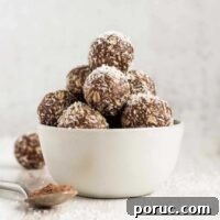 Chocolate Coconut Peanut Butter Energy Bites for Snacks 10 Chocolate peanut butter balls sprinkled with coconut flakes stacked in a small white bowl.