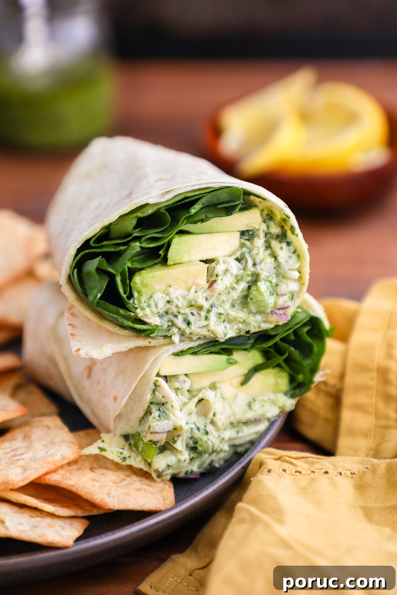 Kale Pesto Recipe: Flavorful Homemade Sauce for Pasta & Sandwiches 4 A pesto chicken salad wrap sitting on a plate with crackers and a jar of homemade pesto