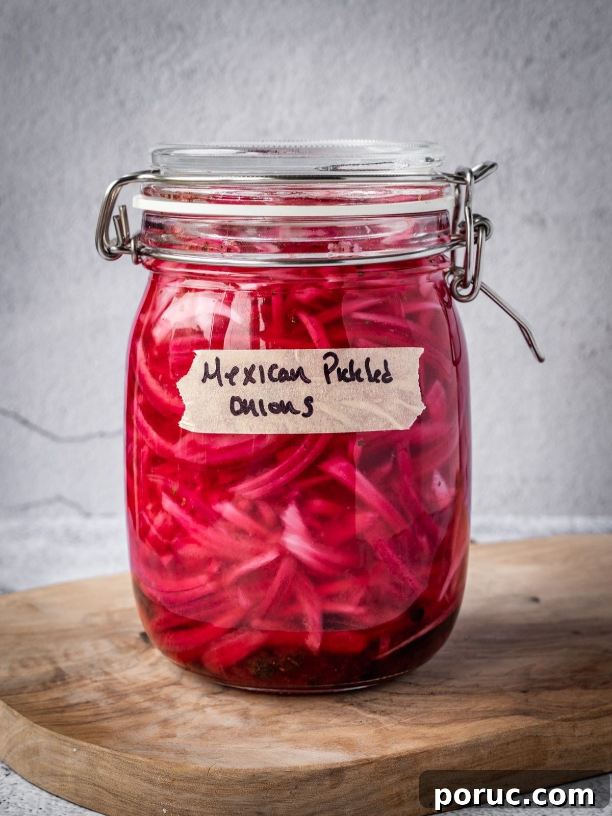 Yucatan-Style Mexican Pickled Red Onions for Tacos & Salads 12 A jar of pickled Mexican onions with a label on a wooden board.