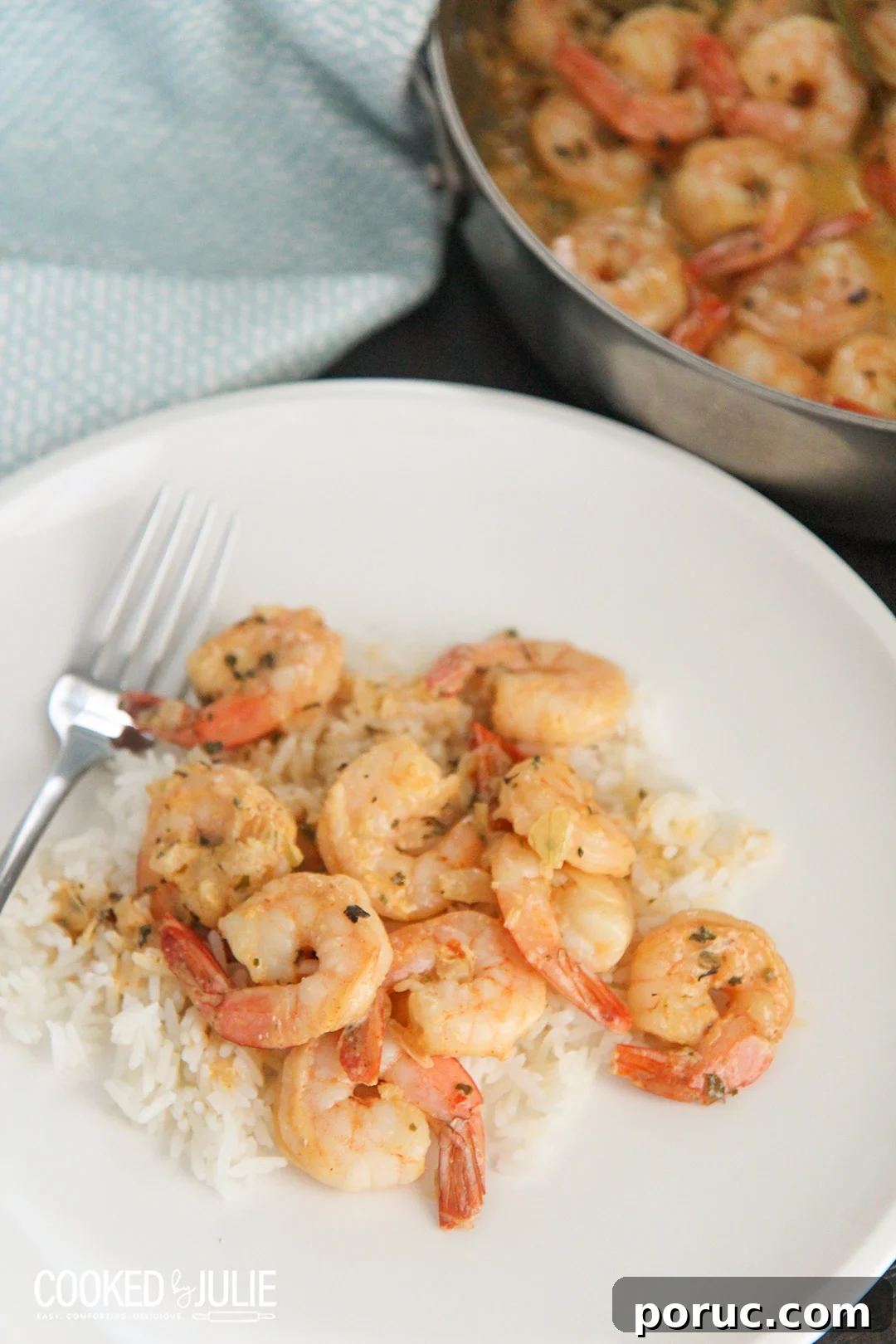 shrimp over white rice on a white plate with a fork 