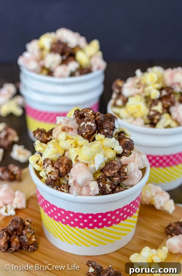 Banana Split Popcorn - this easy chocolate covered popcorn has banana, chocolate, and strawberry flavors. It is an easy recipe to make and enjoy for movie or game nights. A white bowl overflowing with chocolate, strawberry, and banana popcorn and more filled bowls in the background