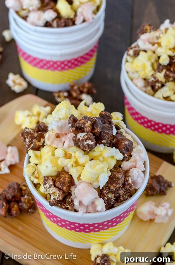 Banana Split Popcorn - chocolate covered popcorn with banana and strawberry flavors makes a delicious and fun snack mix. Easy recipe to make for snacking on. Overhead picture of a white bowl on a wood board filled with chocolate, strawberry, and banana popcorn