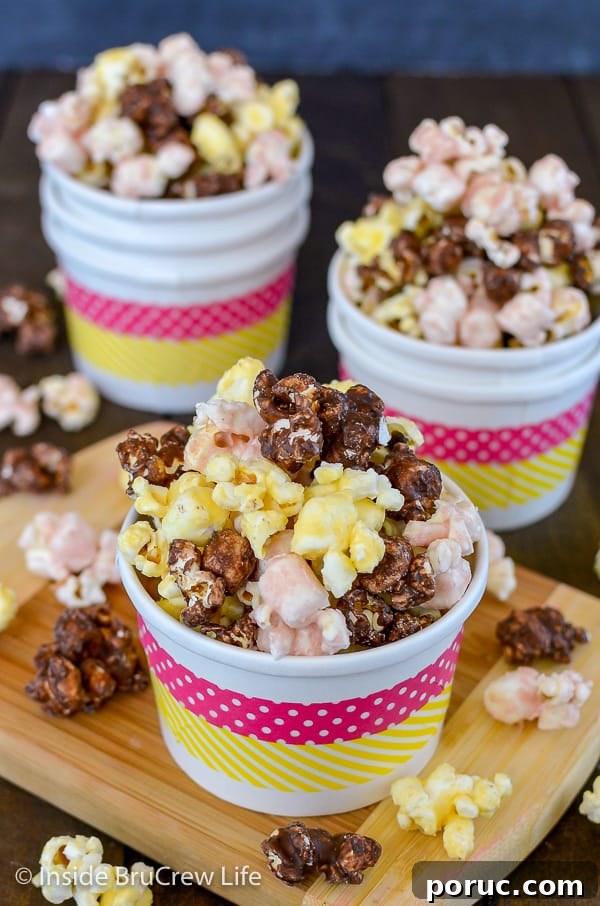 Banana Split Popcorn - this easy chocolate covered popcorn has banana, strawberry, and chocolate covered popcorn mixed together in one bowl. Great recipe to make for movie or game nights. Three white bowls filled with chocolate, banana, and strawberry flavored popcorn