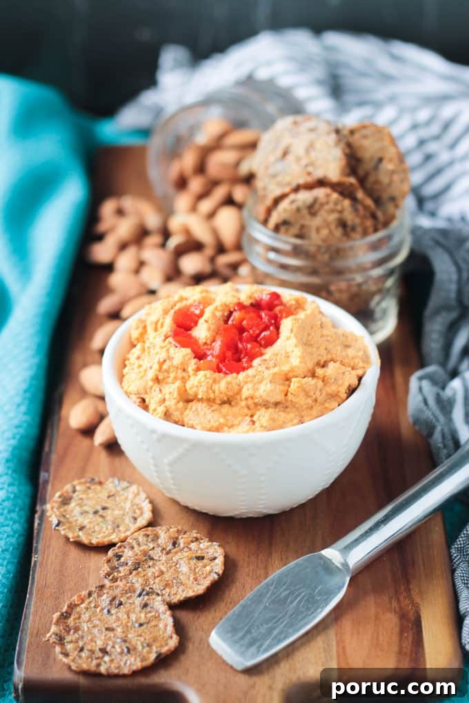 Smoked Almond Cheddar Spread - a delicious and super easy vegan cheddar cheese spread. Only 5 ingredients and made all in the food processor. Spread it on crackers, use it as a sandwich spread, dip fresh fruits and veggies in it - you're gonna love this smoky spread! Bowl of vegan cheddar cheese spread surrounded by crackers and raw almonds.