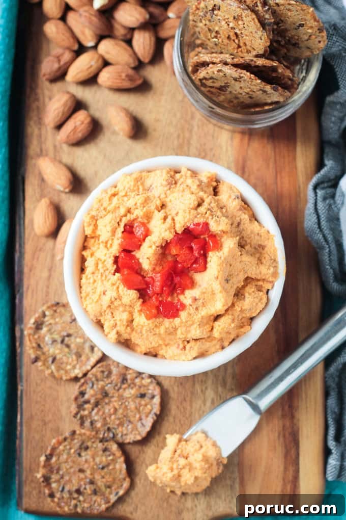 Smoked Almond Cheddar Spread - a delicious and super easy vegan cheddar cheese spread. Only 5 ingredients and made all in the food processor. Spread it on crackers, use it as a sandwich spread, dip fresh fruits and veggies in it - you're gonna love this smoky spread! Overhead view of a bowl of vegan cheddar cheese spread surrounded by crackers and almonds.