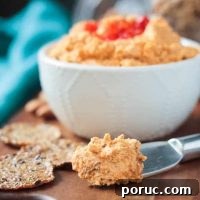 Creamy Vegan Cheddar-Style Cheese Spread for Sandwiches & Dips 2 Metal cheese spreader with vegan cheddar cheese spread. Bowl of cheese spread in the background.