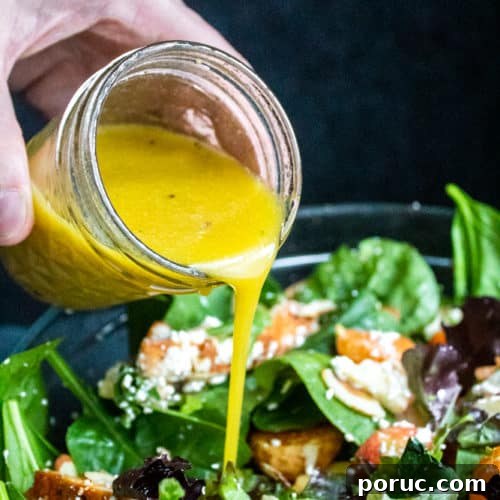Honey Dijon Vinaigrette being poured onto a bowl of salad.