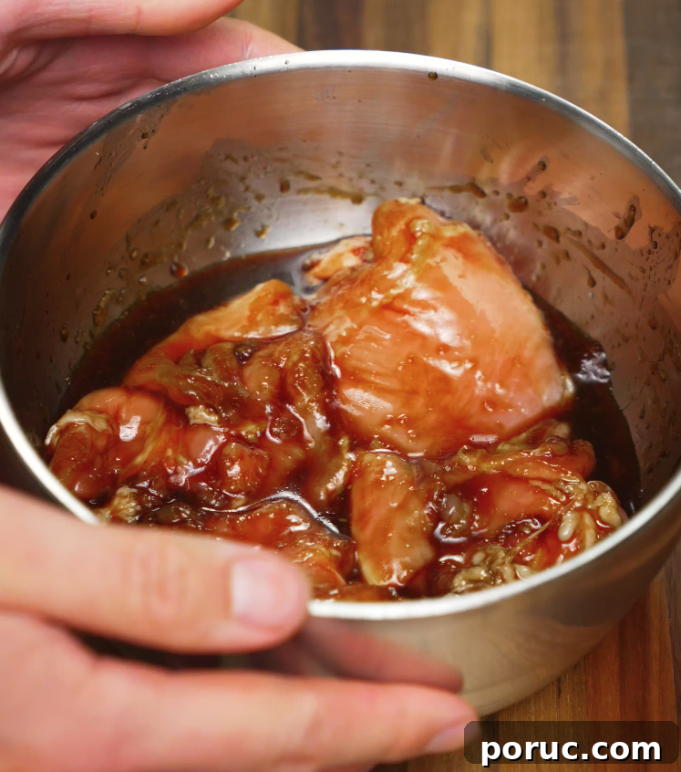 Korean Chicken Bulgogi Recipe: Sweet-Spicy Grilled Chicken 4 Raw chicken thighs soaking in a rich chicken bulgogi marinade inside a stainless steel mixing bowl.