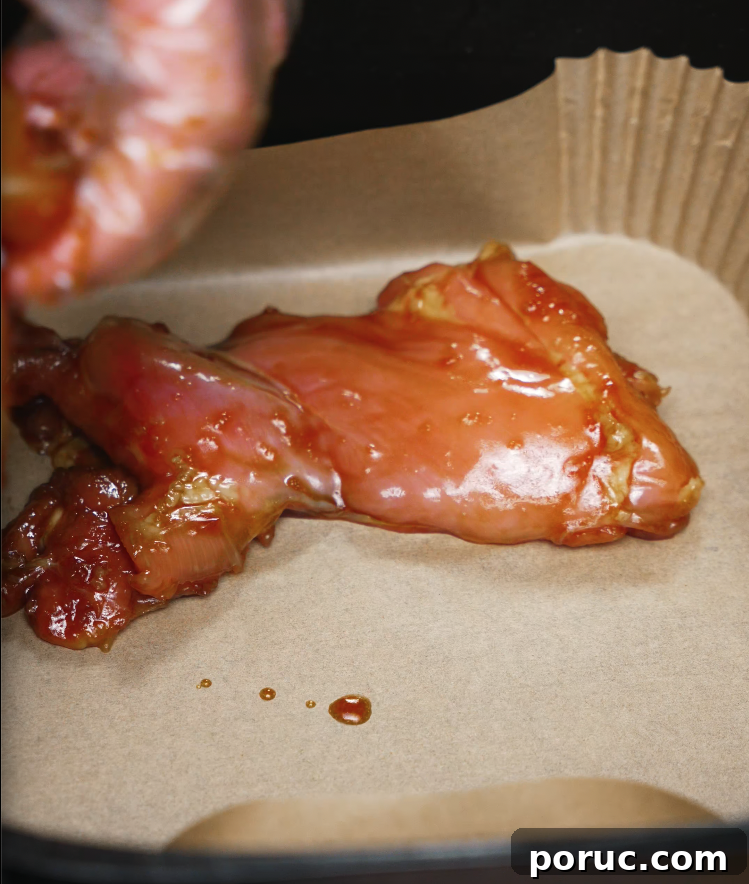 Korean Chicken Bulgogi Recipe: Sweet-Spicy Grilled Chicken 5 Marinated chicken bulgogi thigh placed in an air fryer lined with parchment paper, ready to be cooked.