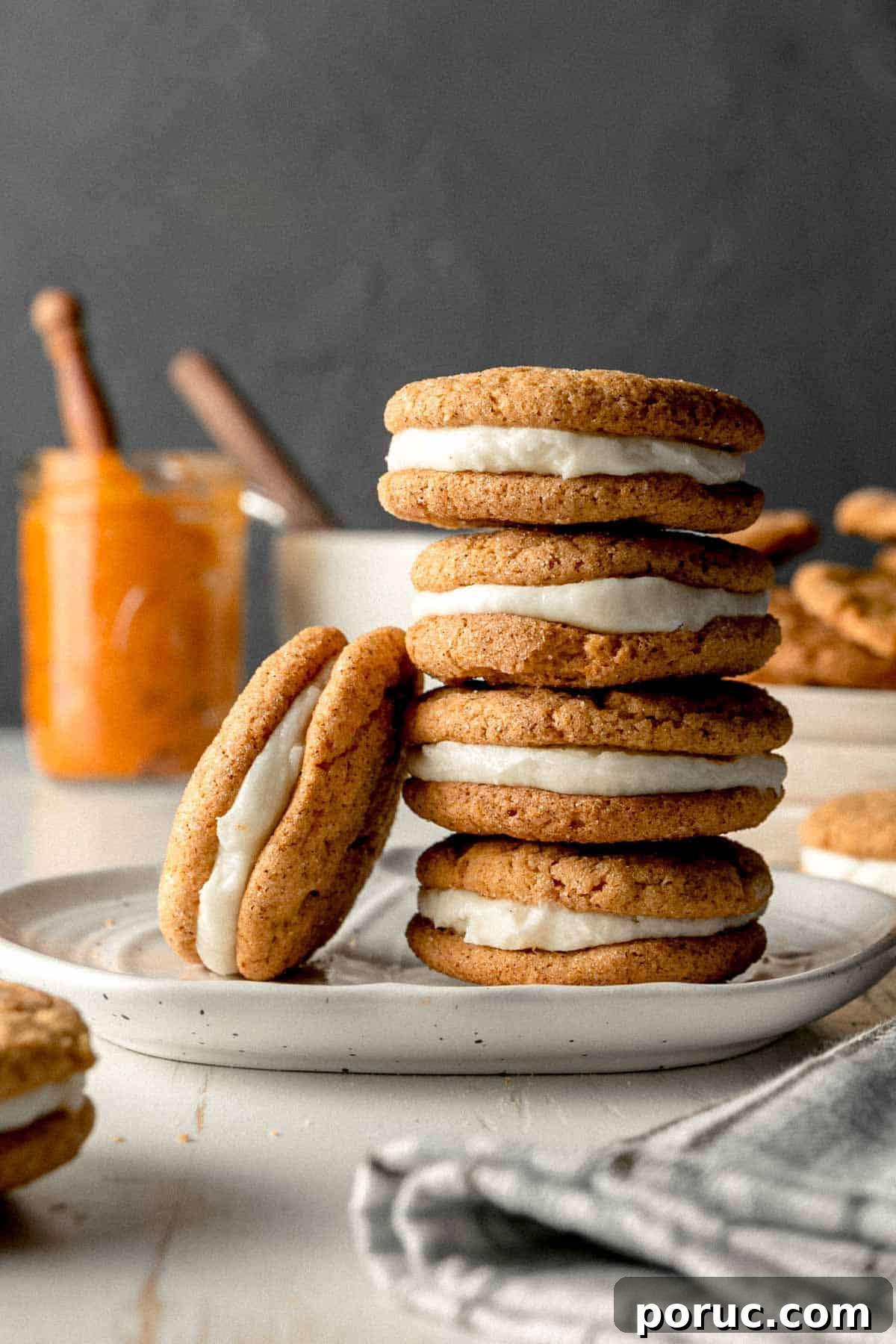 Gluten-Free Pumpkin Cream Pie Recipe for Fall Gatherings 2 A stack of pumpkin cream pies, one cookie leaning against the stack. Pumpkin puree and a frosting bowl in the background.