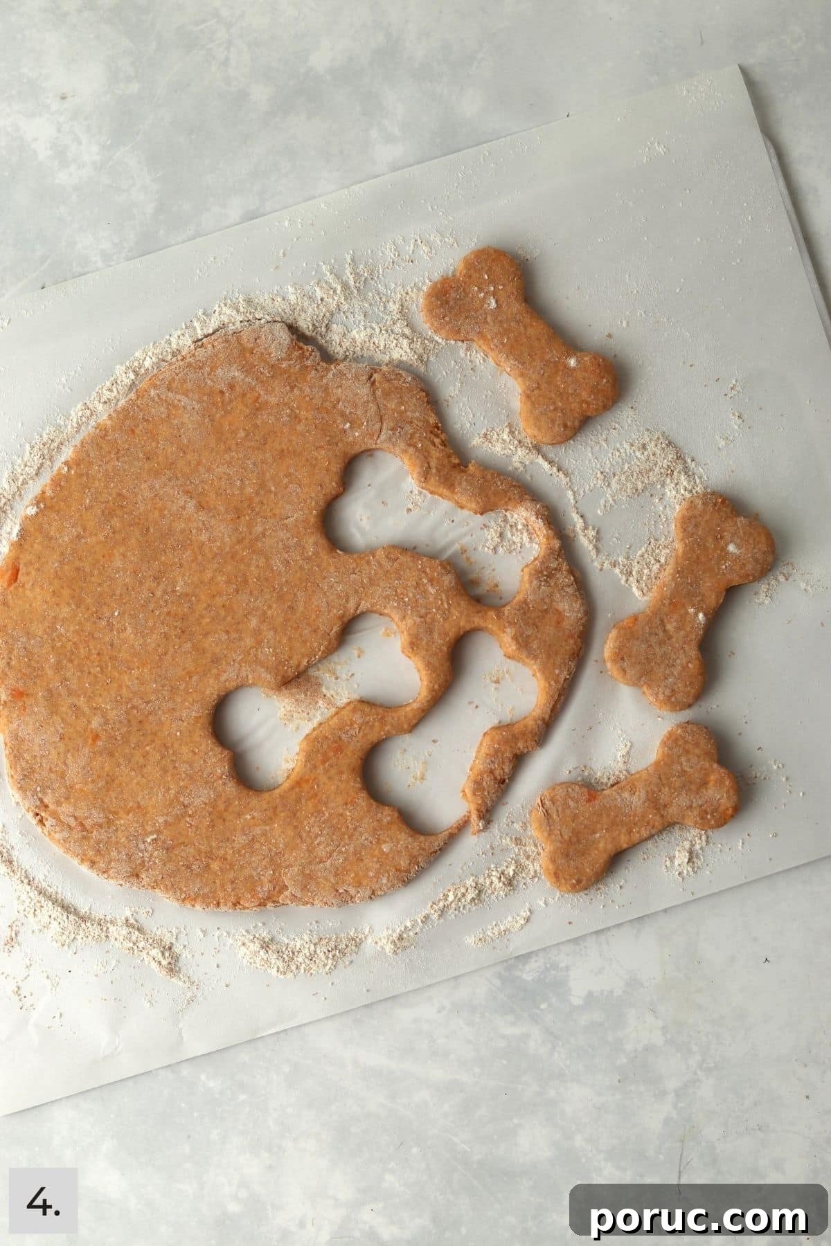 Baked Sweet Potato Dog Treats You Can Make at Home 7 Dog bone cookie cutter shapes cut out from dough.