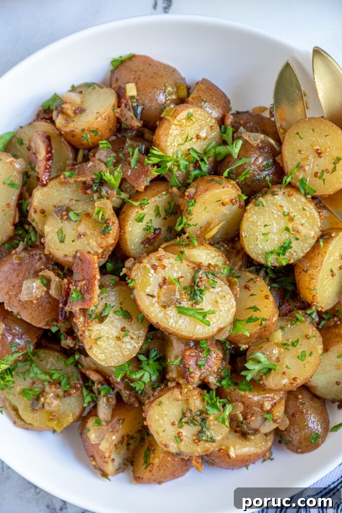 Close up view of German Potato Salad show potatoes in a mustard sauce with bacon and parsley.