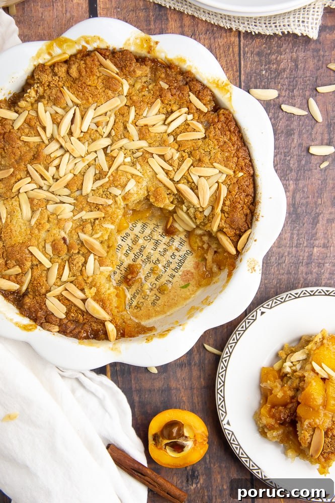 Warm Loquat Cobbler Recipe with Sweet Biscuit Topping 2 a white pie plate with loquat cobbler on a wooden table beside a small gold rimmed white plate with a scoop of cobbler on top.