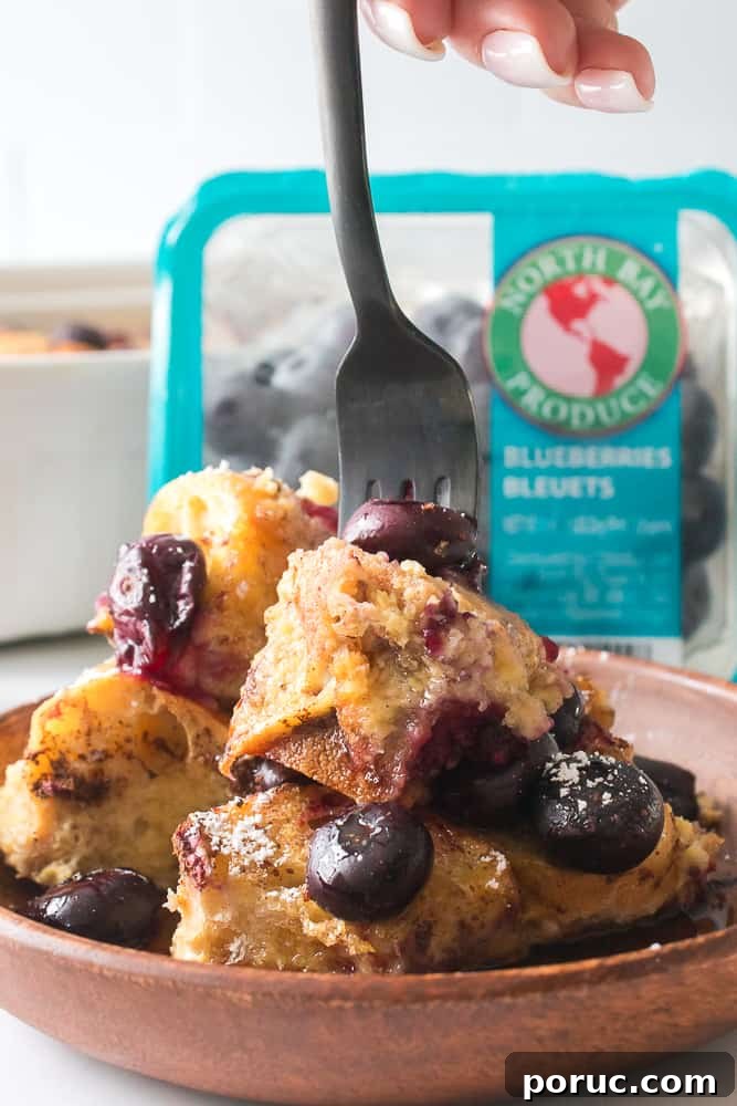 Blueberry French Toast Casserole Recipe for Brunch or Holidays 9 Fork going into part of the blueberry French toast casserole