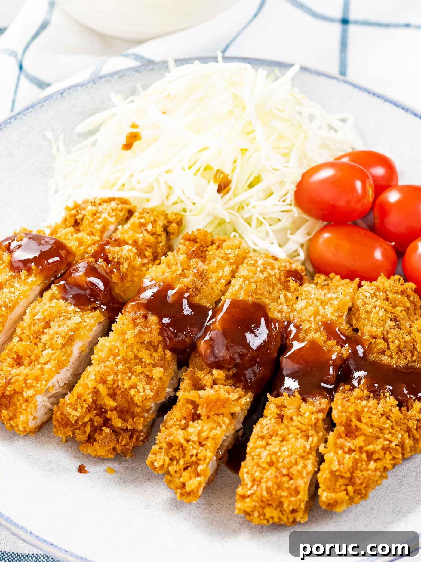The best chicken katsu with crispy breadcrumbs next to shredded cabbage and tomatoes.