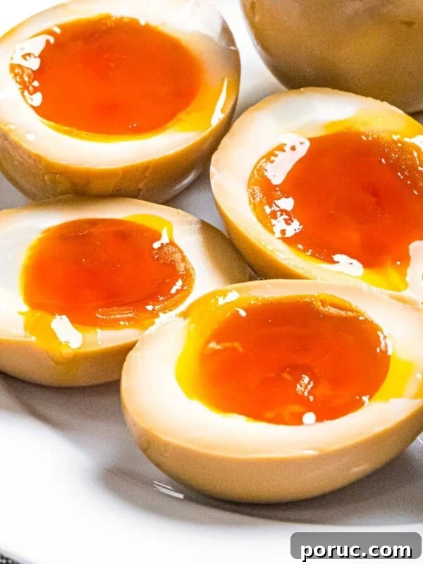Ramen eggs marinated in soy sauce cut in half to reveal soft boiled eggs with runny yolks.