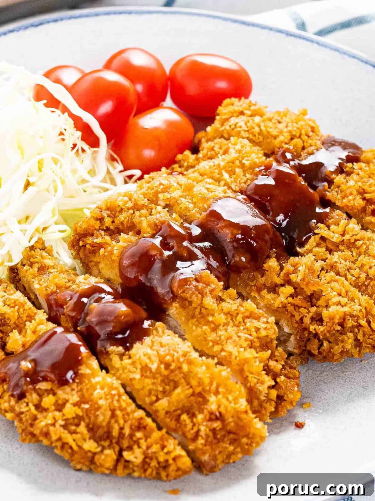 Chicken katsu with panko breadcrumbs, shredded cabbage, and tomatoes.