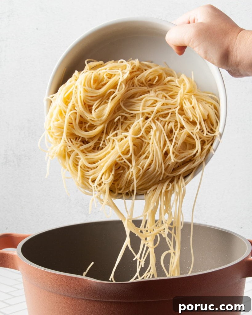 One-Pot Mushroom Pesto Pasta with 4 Ingredients 7 Cooked pasta being tipped into a pot.