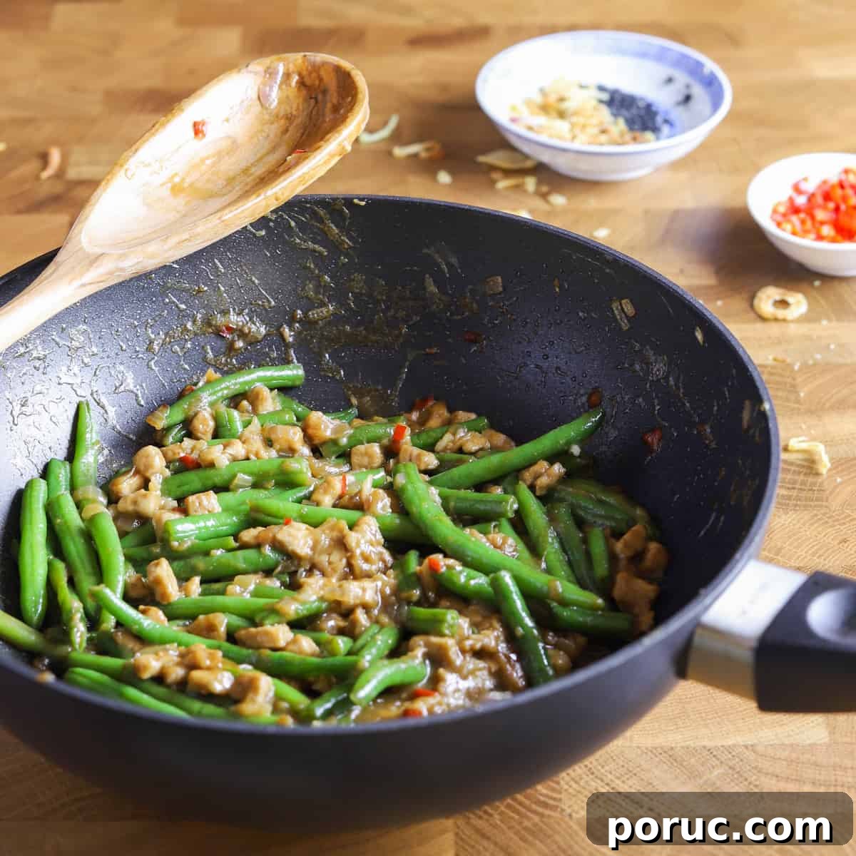 Chinese-Style Green Beans with Crispy Tempeh (Vegan Recipe) 8 photo of a wok containing vegan chinese green beans and tempeh recipe on a butcher block surface