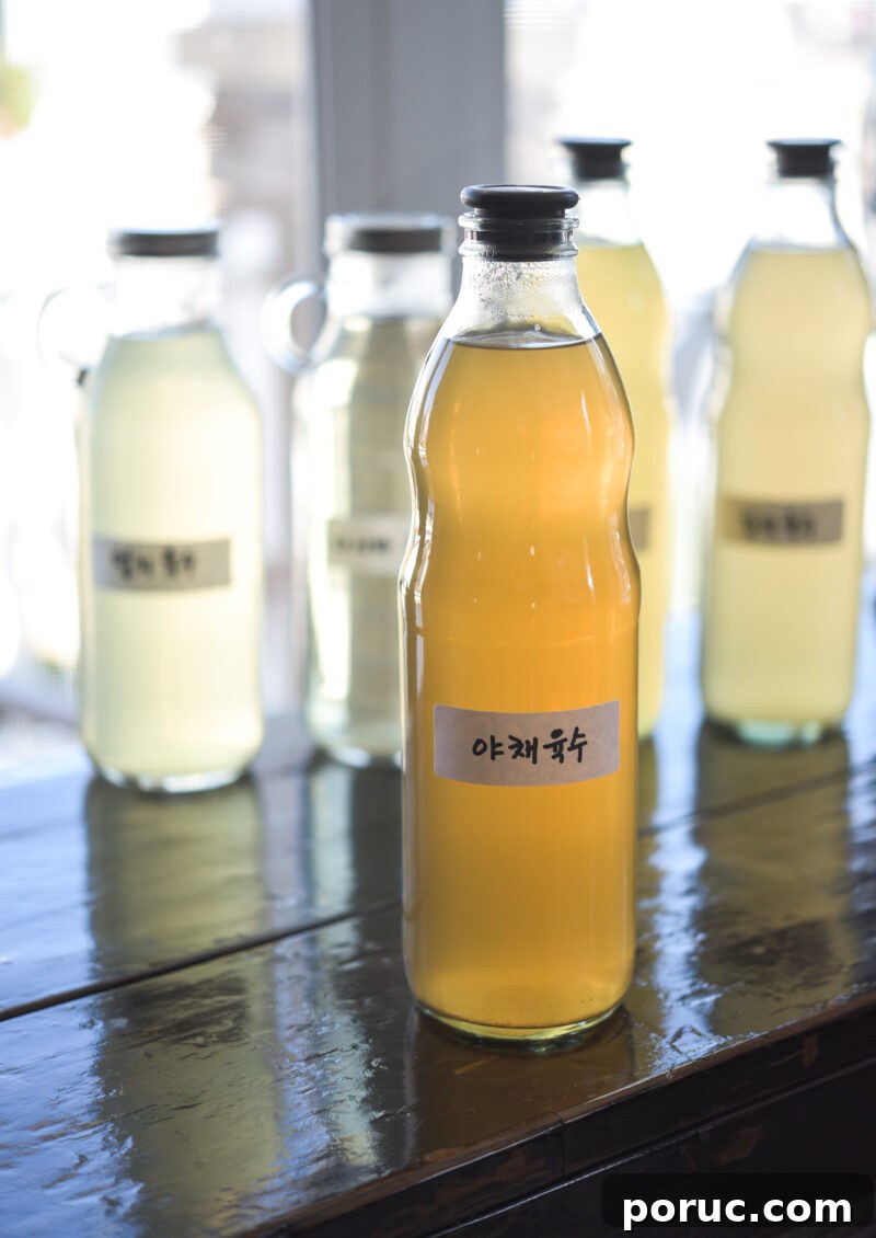 5 Essential Korean Soup Stocks for Authentic Korean Cooking 13 Vegetable stock is showing its golden hue through a glass bottle with a Korean label attached.