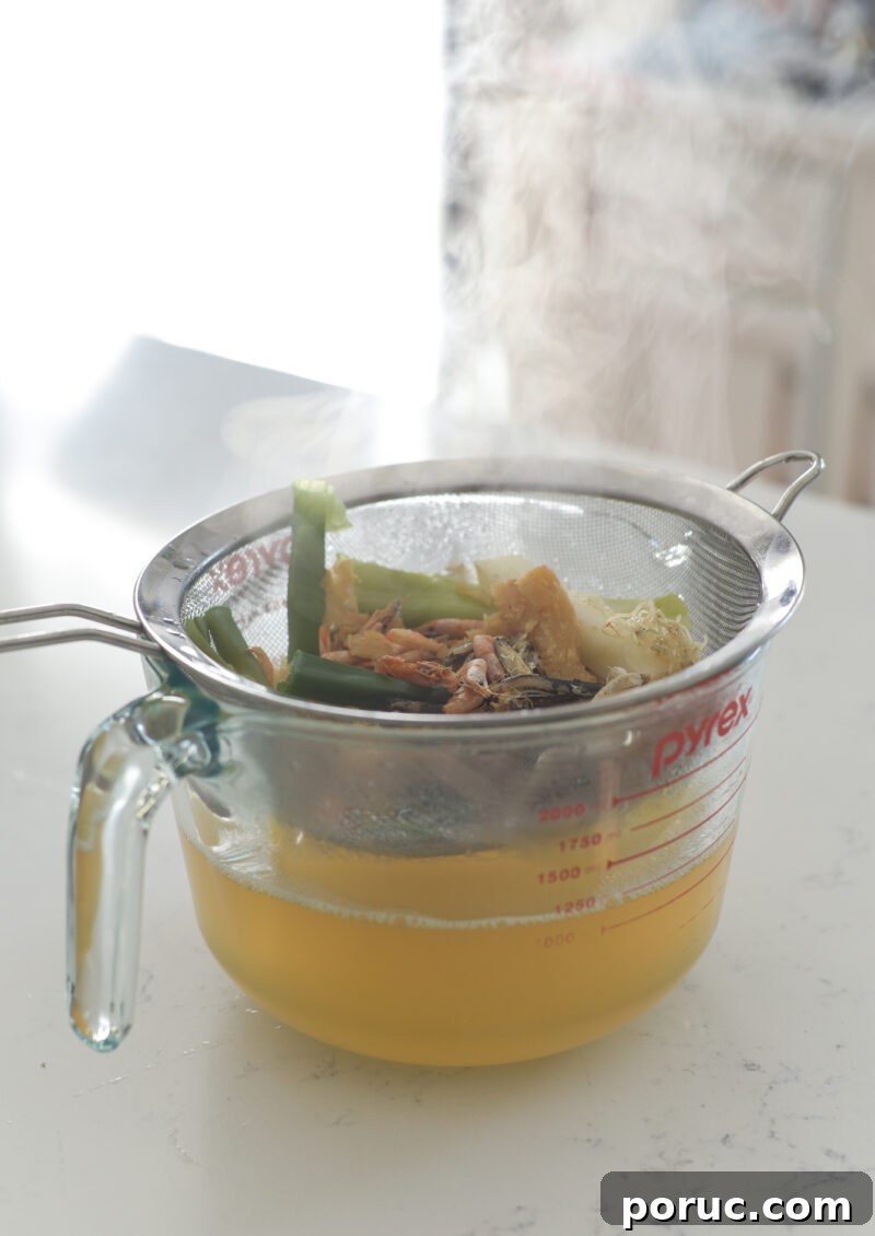 5 Essential Korean Soup Stocks for Authentic Korean Cooking 19 A mesh strainer over a glass bowl is holding the debris of stock and reserving the liquid.