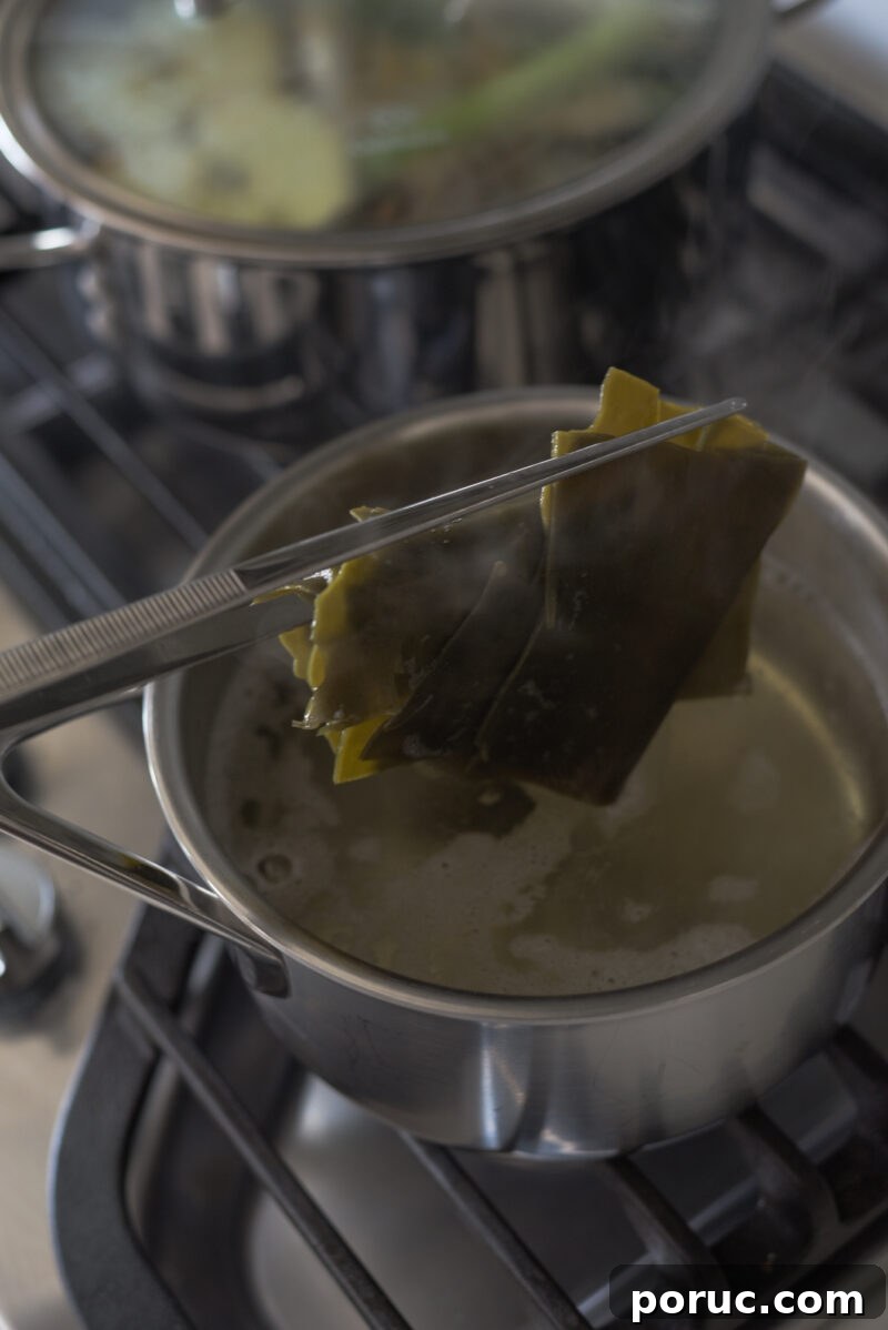 5 Essential Korean Soup Stocks for Authentic Korean Cooking 6 Kitchen tongs are removing the sea kelp from the simmering stock in a pan.