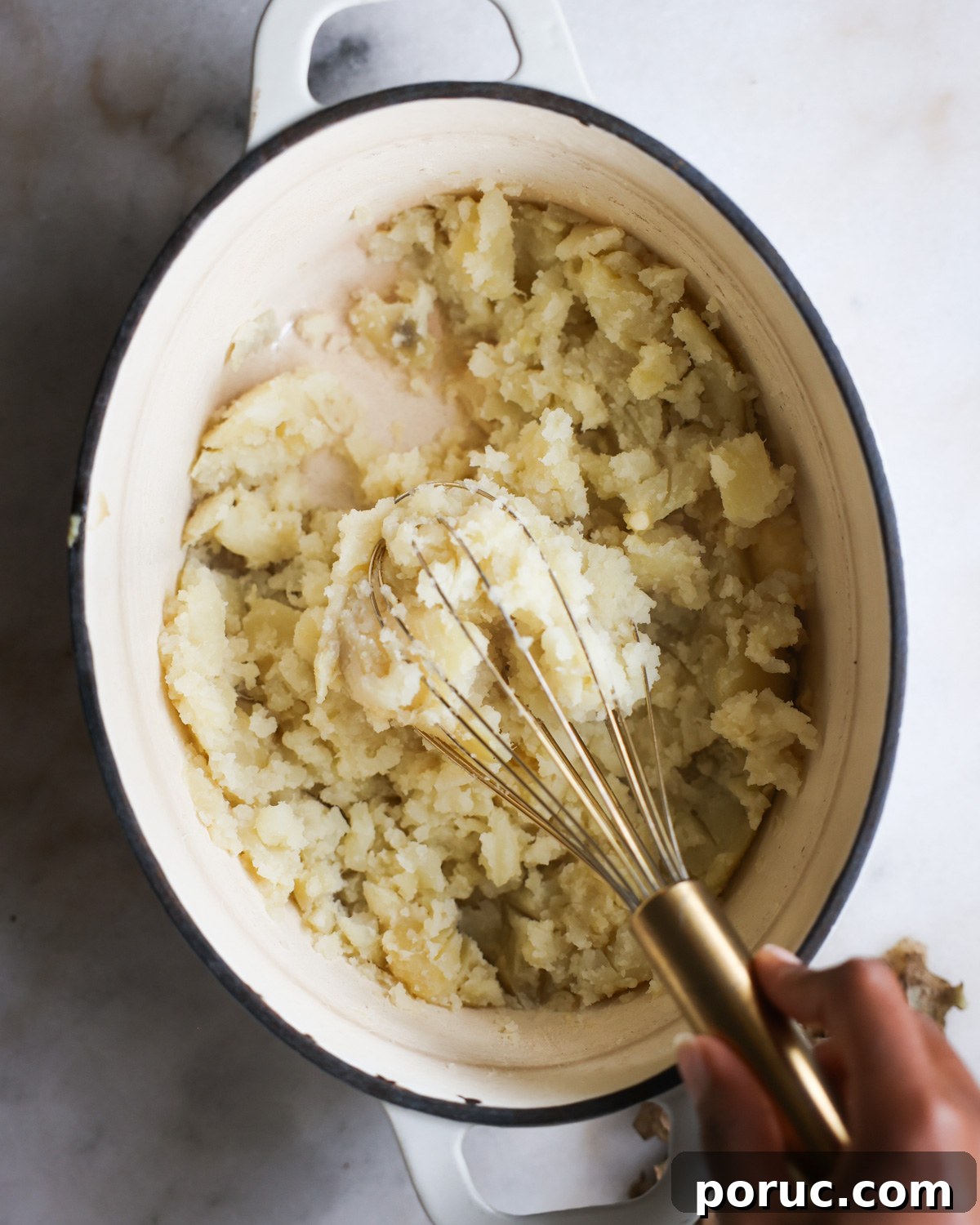 Fluffy Vegan Mashed Potatoes Recipe for Creamy Comfort 10 overhead of a hand using a whisk to mash potatoes