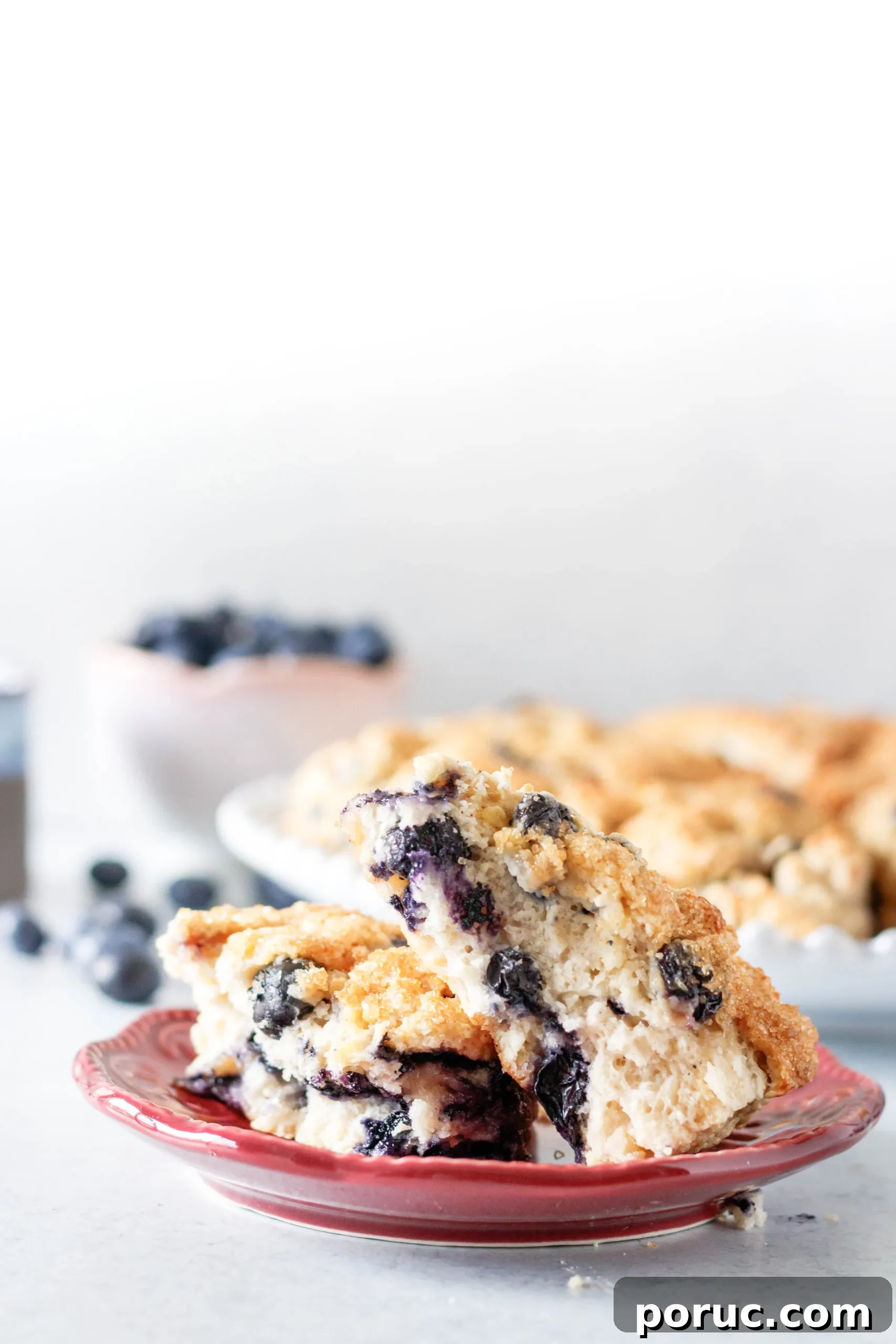 Tender Fluffy Blueberry Scones Recipe — Step-by-Step Guide 6 Scone cut in half on a maroon plate. This picture shows the interior texture of the scones and tender crumb
