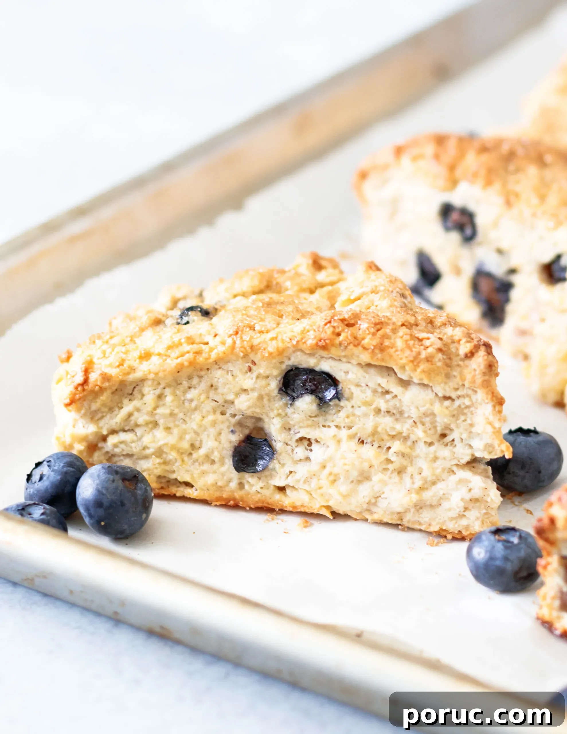 Tender Fluffy Blueberry Scones Recipe — Step-by-Step Guide 4 Close up of the blueberry scones on a rimmed baking sheet to show how fluffy they get during baking