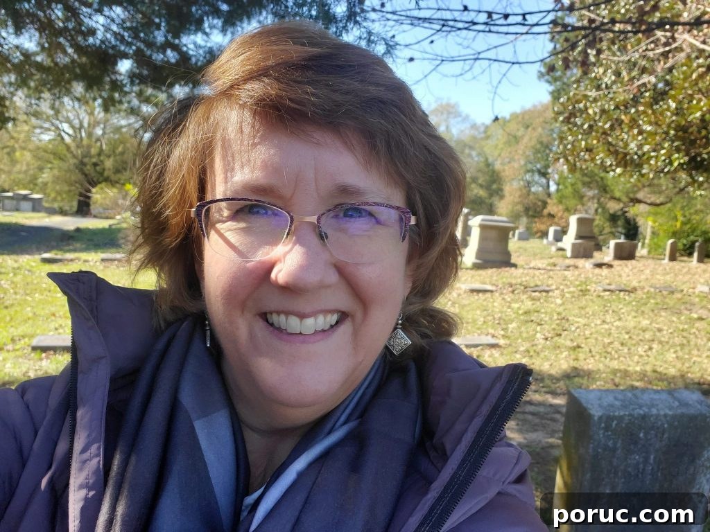 Lisa Lisson - woman with glasses and brown hair - taking selfie in a cemetery.