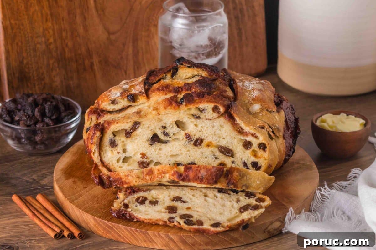 Sourdough Cinnamon Raisin Loaf — Soft, Sweet, Perfect Spice 2 Golden brown sourdough cinnamon raisin bread with visible raisins and cinnamon swirls, cooling on a cutting board. Hostess At Heart