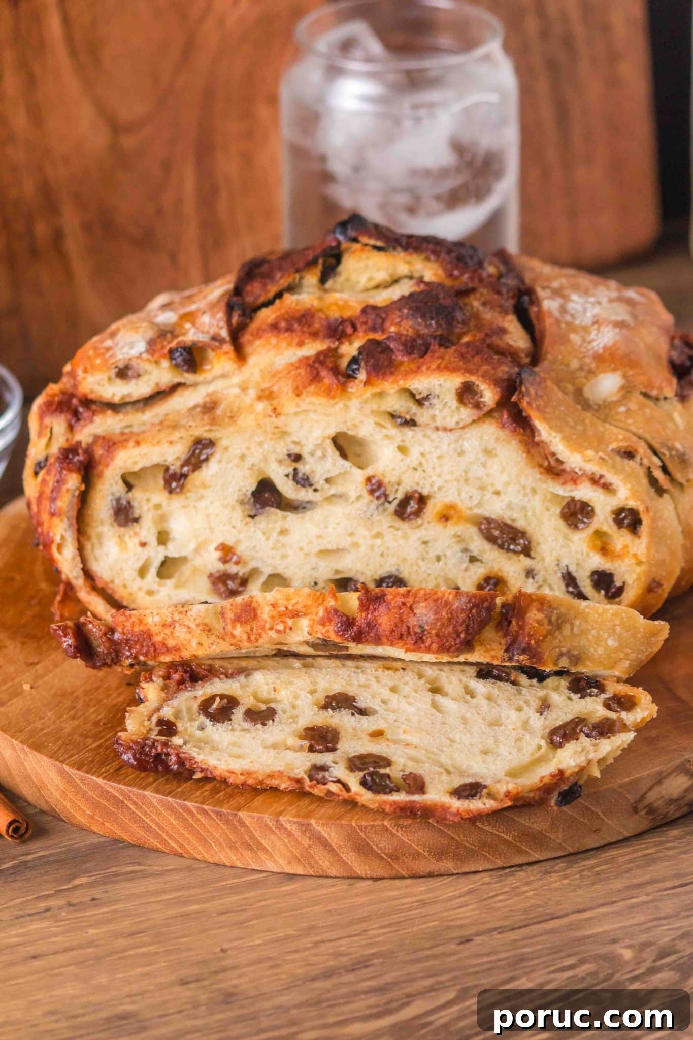 Sourdough Cinnamon Raisin Loaf — Soft, Sweet, Perfect Spice 16 Front view of a loaf of overnight cinnamon raisin sourdough bread sitting on a cutting board with the first two slices cut showing plump raisins and cinnamon swirls throughout a tender crumb. Hostess At Heart
