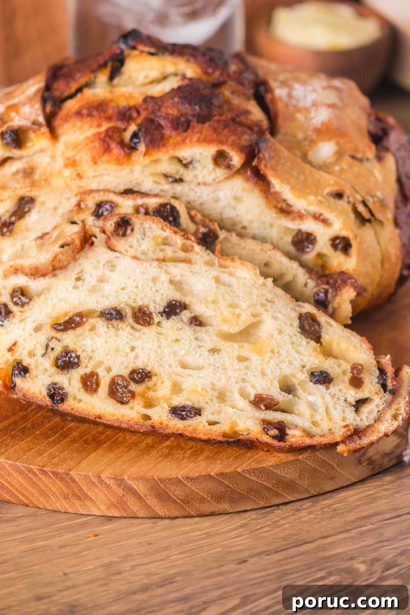 Sourdough Cinnamon Raisin Loaf — Soft, Sweet, Perfect Spice 17 Front view of a loaf of raisin cinnamon sourdough bread sitting on a cutting board with the first two slices cut showing plump raisins and cinnamon swirls throughout a tender crumb. Hostess At Heart