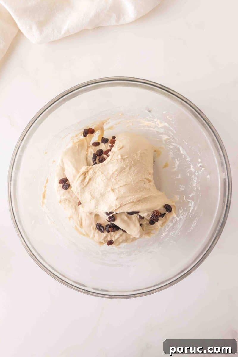Sourdough Cinnamon Raisin Loaf — Soft, Sweet, Perfect Spice 9 Sticky sourdough bread dough in a mixing bowl with dark raisins after the first fold - Hostess At Heart