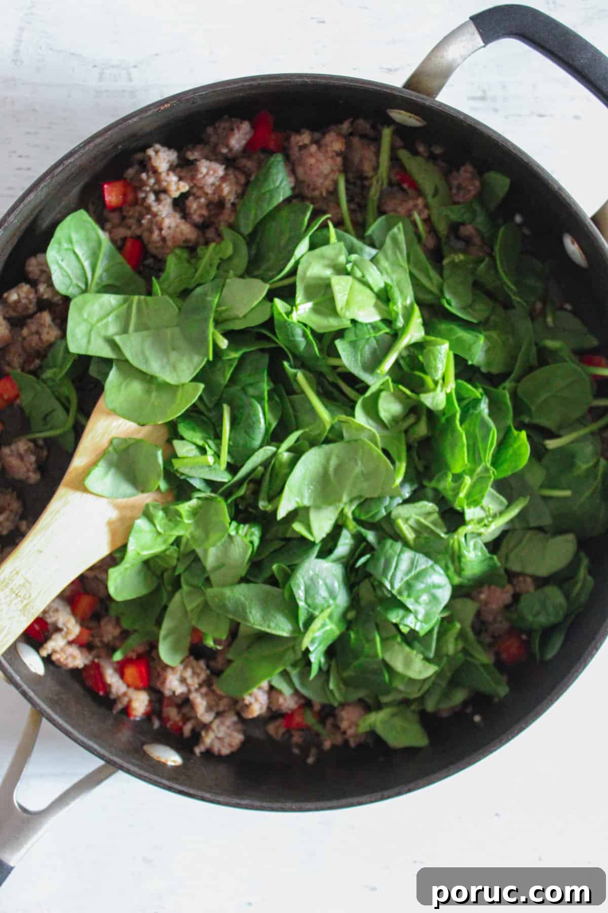Meatless Gluten-Free Sausage Casserole Recipe for Busy Nights 6 adding a bunch of spinach to the skillet.