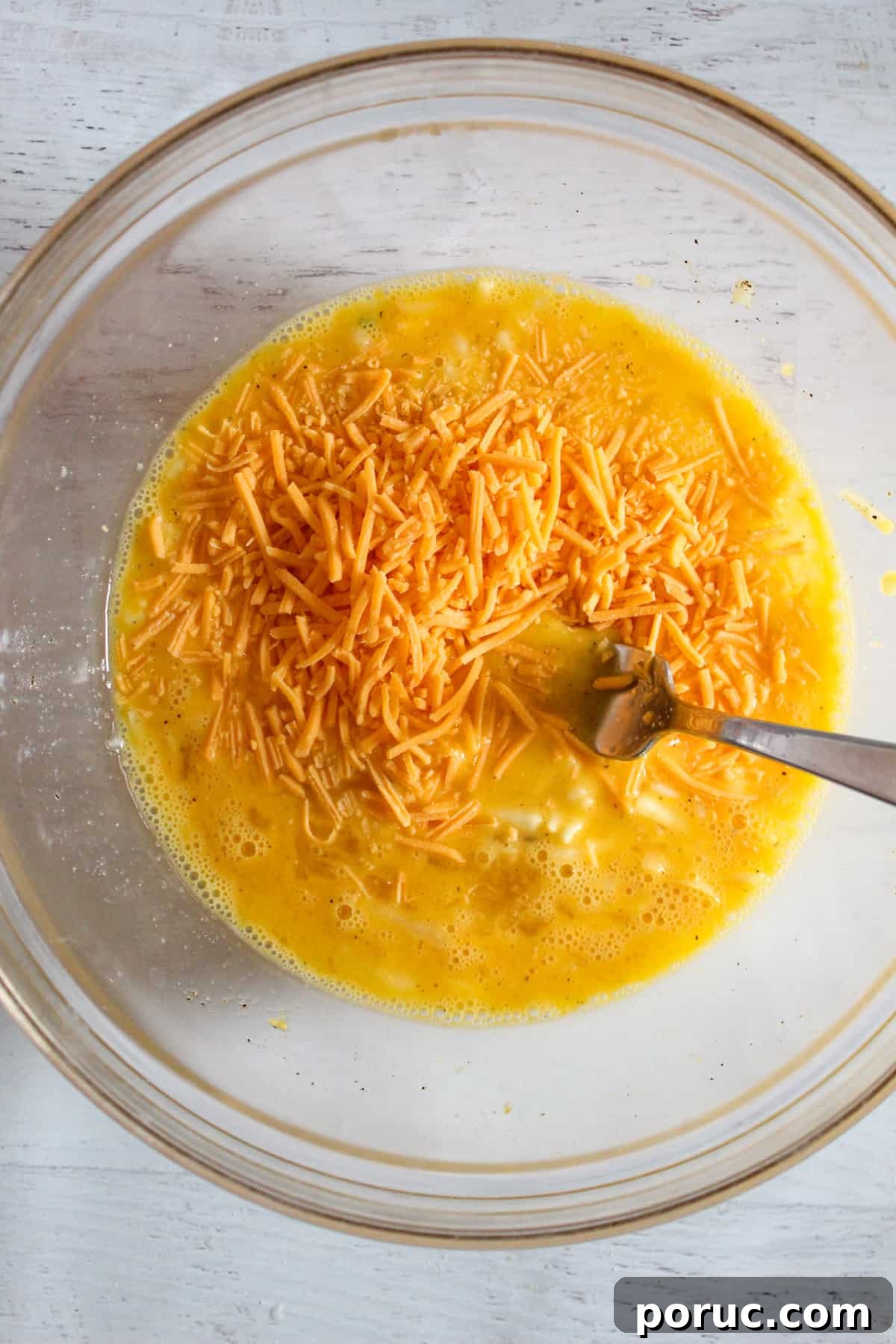 Meatless Gluten-Free Sausage Casserole Recipe for Busy Nights 8 adding shredded cheese to a glass bowl of eggs.