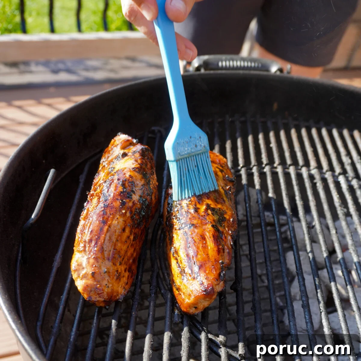 Sweet and Savory Pork Tenderloin Recipe with Glaze and Herbs 7 Brushing marinade over grilled pork tenderloin.
