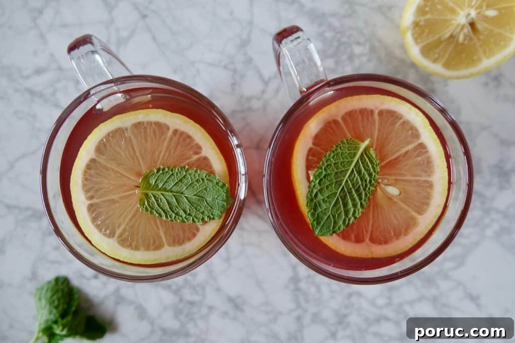 Honey Citrus Mint Tea — Copycat Starbucks Medicine Ball Recipe 4 Birdseye view of two glass mugs filled with tea and garnished with lemon and mint.