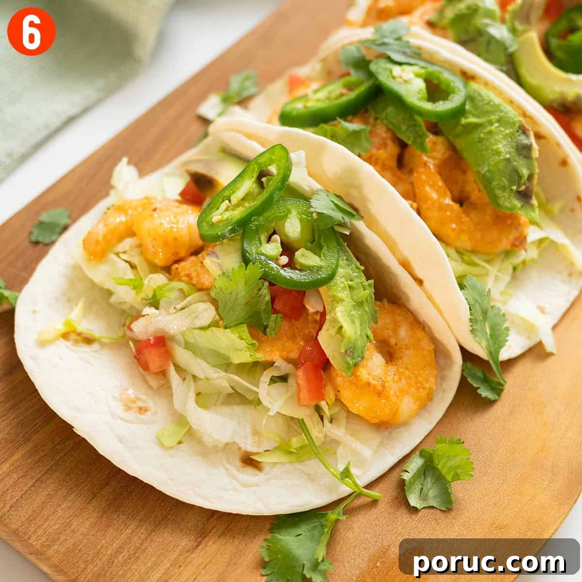 Volcano Shrimp Tacos: Spicy Grilled Shrimp with Lava Sauce 9 Volcano shrimp tacos on a cutting board topped with cilantro, tomatoes, jalapeno, and avocado.
