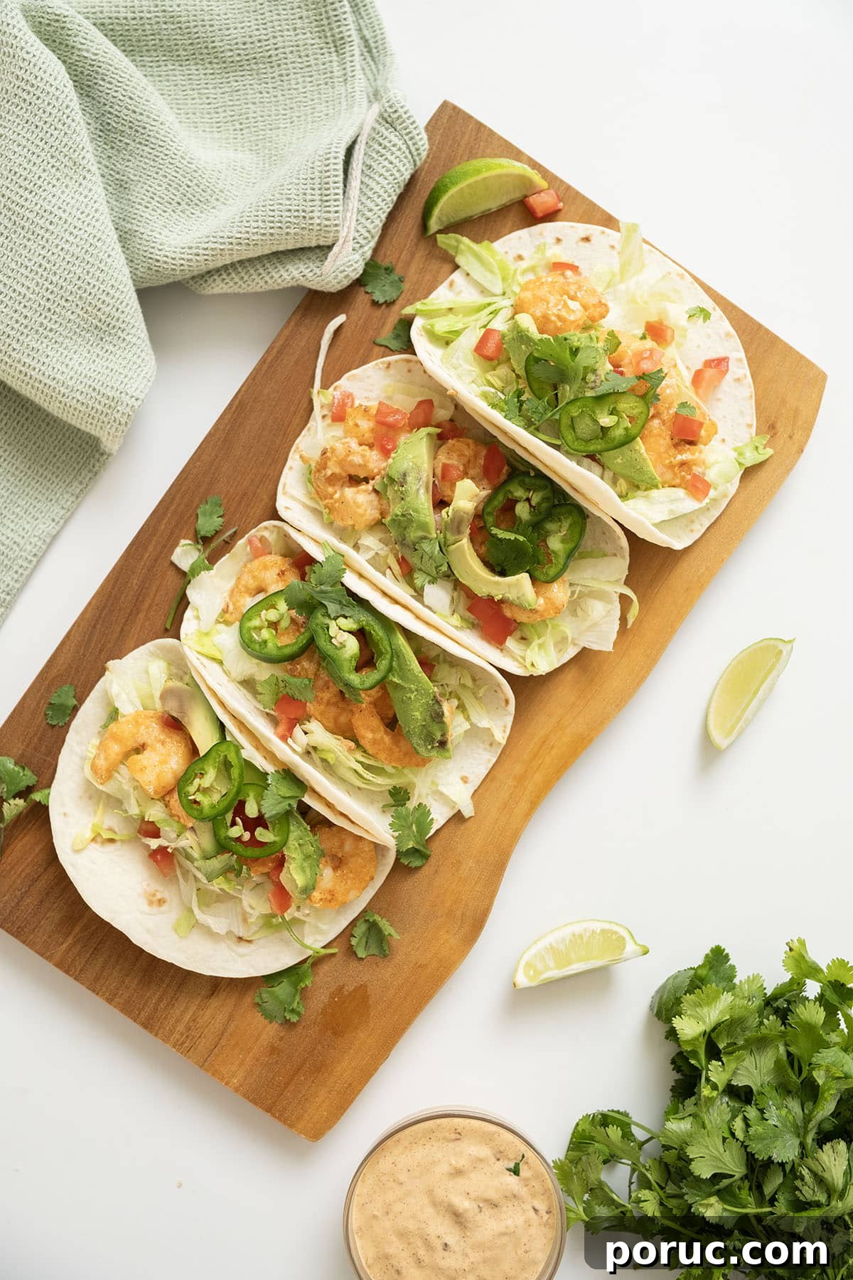 Volcano Shrimp Tacos: Spicy Grilled Shrimp with Lava Sauce 10 Volcano shrimp tacos on a cutting board topped with cilantro, tomatoes, jalapeno, and avocado.