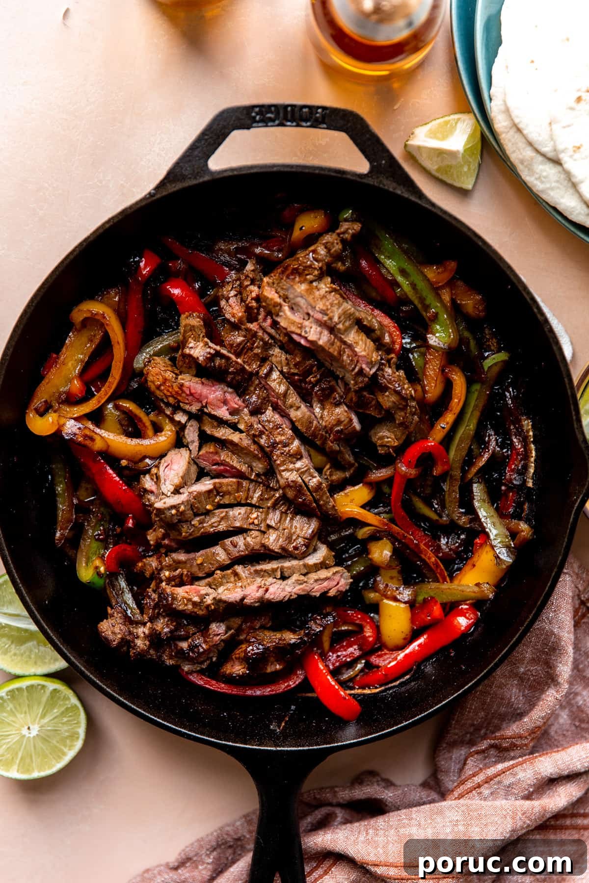 Sizzling Steak Fajitas Recipe with Peppers and Onions 2 Large cast iron skillet filled with sliced grilled steak and grilled bell peppers and onions.