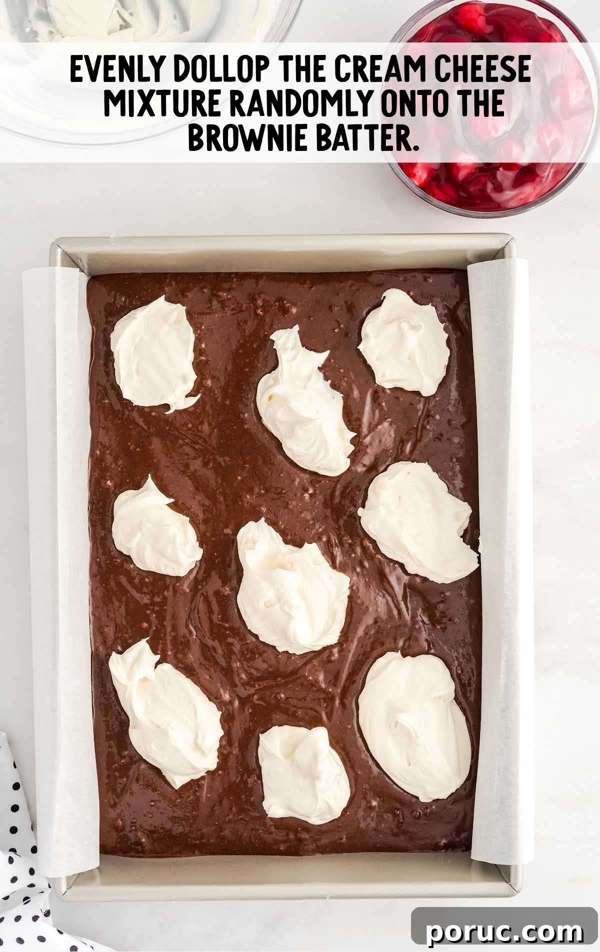 scoops of cream cheese mixture placed on top of the brownie mixture