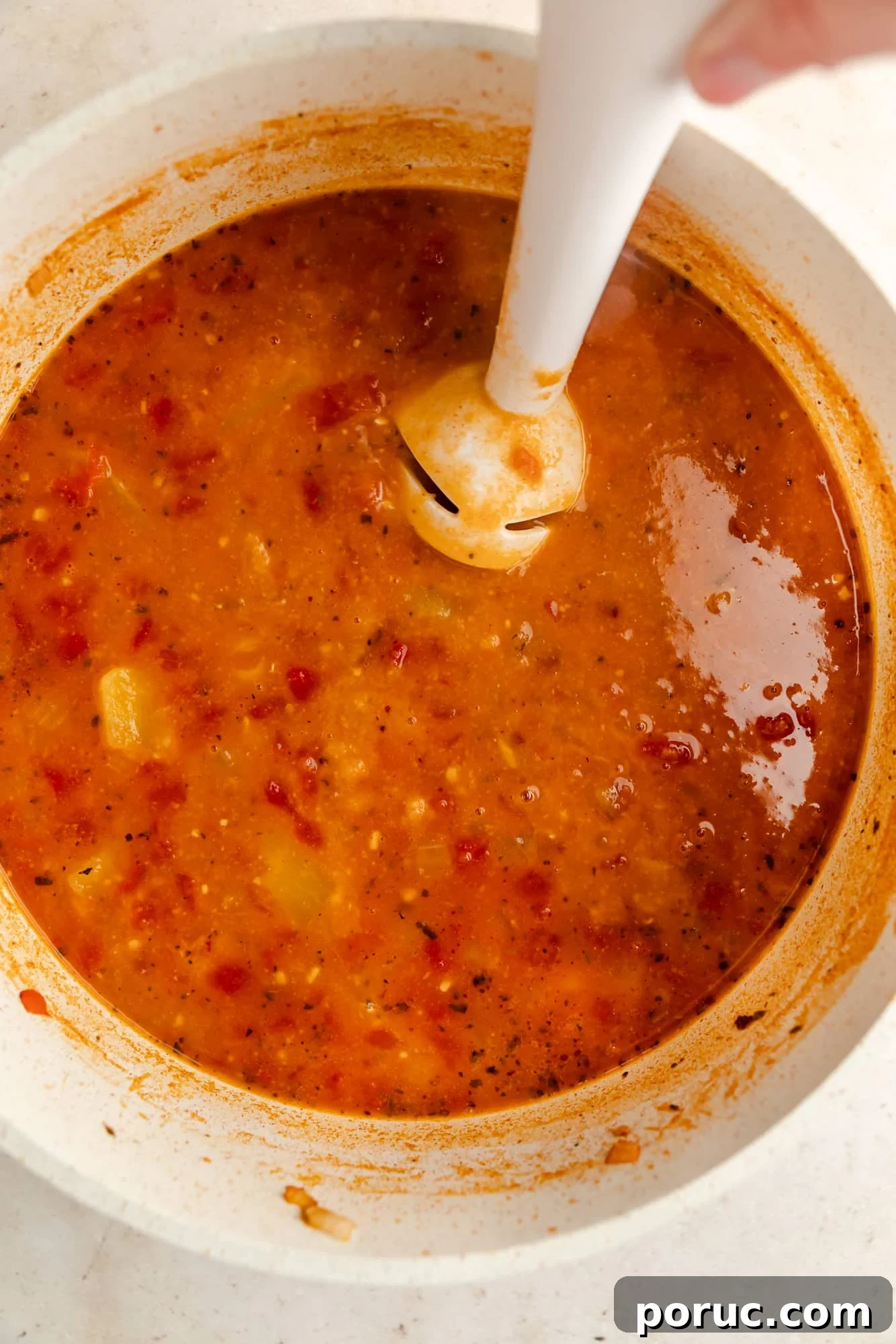 Hearty Italian Chickpea Soup Recipe for Comforting Weeknight Meals 7 using a white immersion blender to blend chickpea soup in a white pot.